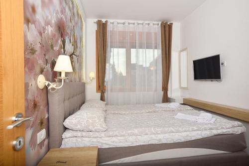a small bedroom with a bed and a television at Vila Mina in Zlatibor