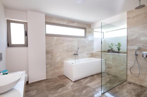 a bathroom with a white tub and a glass shower at Sea Queen Villa in Kato Daratso