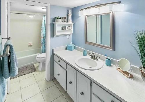 a bathroom with a sink and a toilet and a mirror at Immaculate 2BR 2 Bath Beachside Condo in Daytona Beach Shores