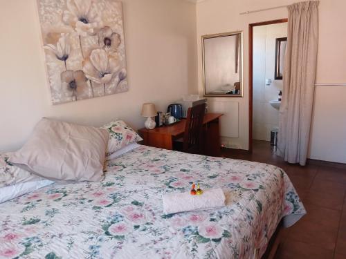 a bedroom with a bed with a floral bedspread at White Rose Guest House in Vanderbijlpark