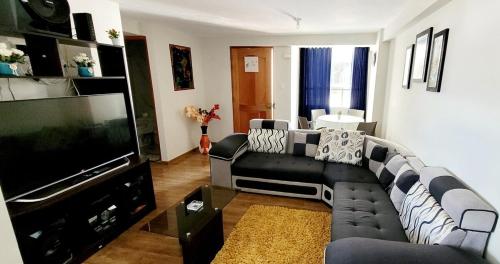 a living room with a couch and a flat screen tv at Departamento zona residencia cusco in Cusco