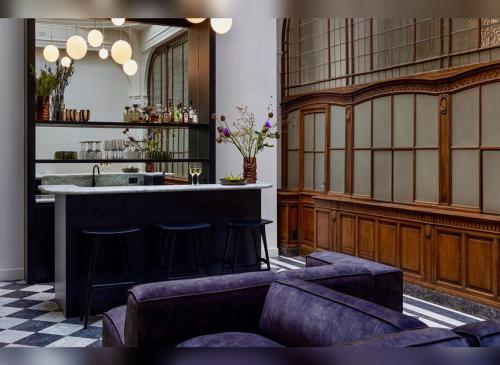 a kitchen with a bar with stools and a sink at De Gulden Poorte, a LXRYHOME Hotel Collection in Antwerp