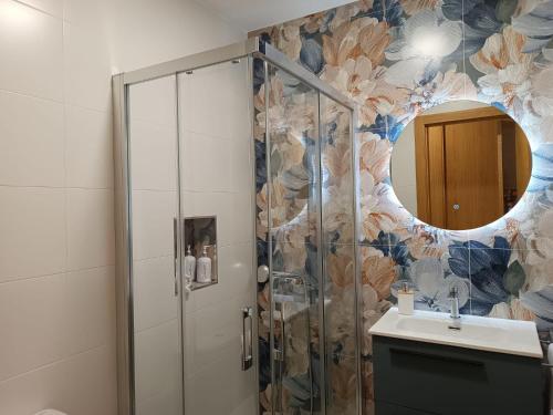 a bathroom with a shower with a sink and a mirror at La Tinaja casa rural in Hernansancho