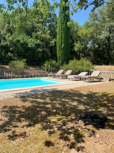 a swimming pool with lounge chairs next to a tree at La bergerie in Grignan