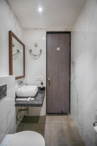 a bathroom with a wooden door and a sink at The White Seasons in Gwalior