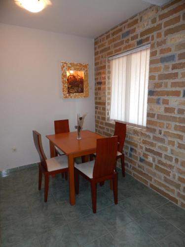 a dining room table with chairs and a brick wall at Contessa Apartments in Budva