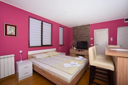 a bedroom with a large bed with a pink wall at Vila Mina in Zlatibor