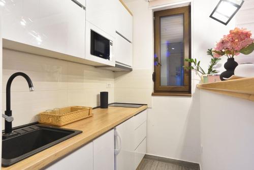 a kitchen with white cabinets and a sink and a window at Vila Mina in Zlatibor