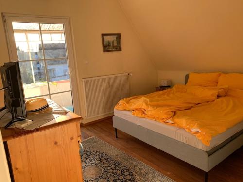 a bedroom with a bed with an orange comforter and a television at Freistehendes Haus mit grossem Garten zur alleinigen Nutzung in Großkrotzenburg