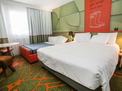 a hotel room with two beds and a table at Ibis Styles Lisieux Normandie in Lisieux