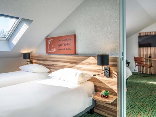 a hotel room with two beds and a table at Ibis Styles Lisieux Normandie in Lisieux