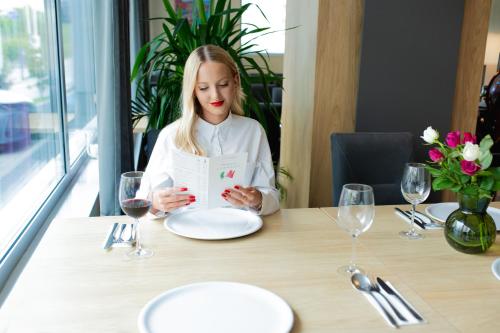 a woman sitting at a table reading a menu at Hotel CONRAD Comfort in Kraków