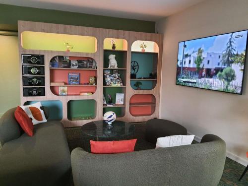 a living room with a couch and a tv at Ibis Styles Lisieux Normandie in Lisieux