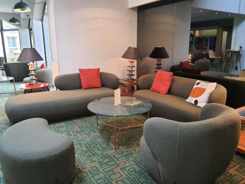 a living room with couches and chairs and a table at Ibis Styles Lisieux Normandie in Lisieux