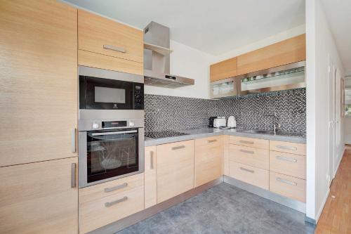 a kitchen with wooden cabinets and a microwave at Apt Cosy - AC-1CH-4P - Suresnes-Parc du Chateau in Suresnes