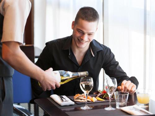 a man pouring a glass of wine on a table at Novotel Belfort Centre Atria in Belfort