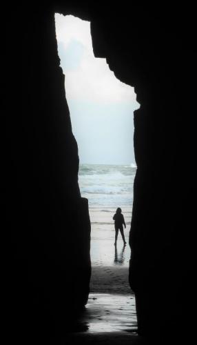 a person walking on the beach through a cave at Surat Bay Lodge by the Sea/Backpackers Hostel in Owaka