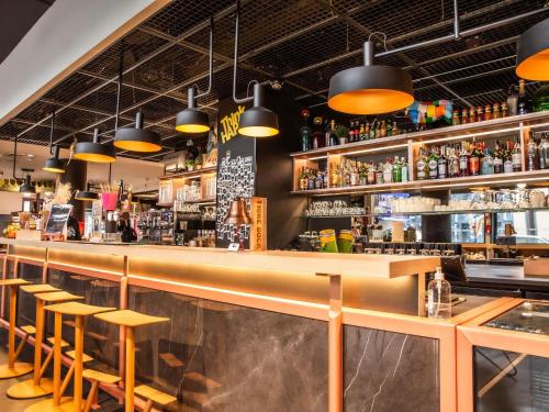 a bar with wooden bar stools and lights at ibis Paris Bercy Village in Paris