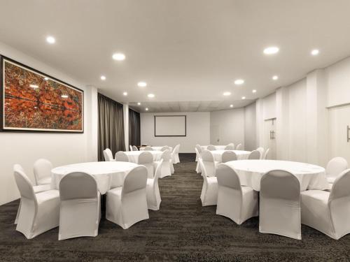 a conference room with white tables and white chairs at Novotel Darwin CBD in Darwin