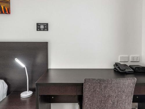 a desk with a lamp and a chair in a room at Mercure Townsville in Townsville