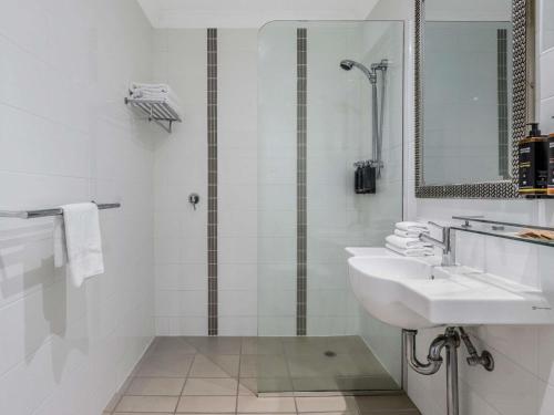a white bathroom with a sink and a mirror at Mercure Townsville in Townsville