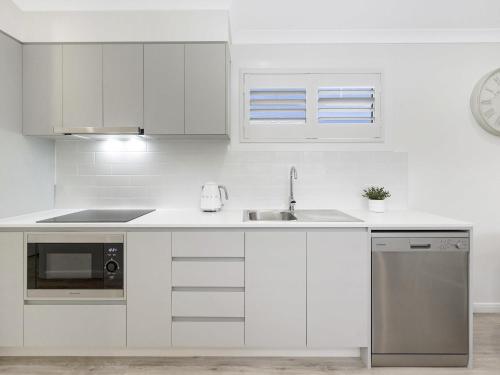 a white kitchen with a sink and a microwave at Mercure Townsville in Townsville
