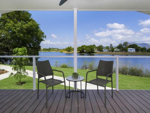 two chairs and a table on a deck with a view of a lake at Mercure Townsville in Townsville