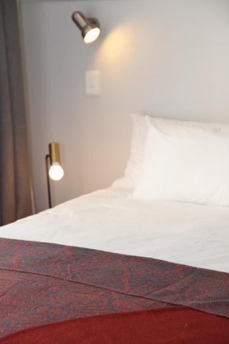 a bedroom with a white bed with a red rug at Modern Family Golf Lodge in Winelands Paradise in Paarl