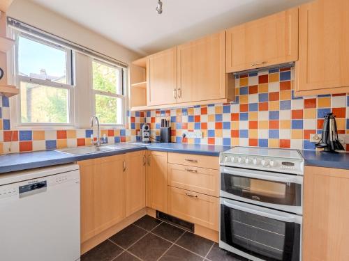 a kitchen with wooden cabinets and a stove top oven at Pass the Keys Central Mews house with parking in Bath