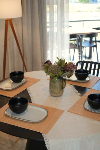 a table with three plates and a vase with flowers on it at Modern Family Golf Lodge in Winelands Paradise in Paarl