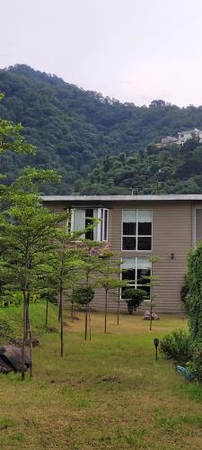 a house in a field with trees in front of it at Aristaa Morni Hills: Pristine Stay in the Wild in Morni
