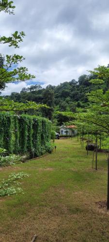 a field with trees and a house in the distance at Aristaa Morni Hills: Pristine Stay in the Wild in Morni