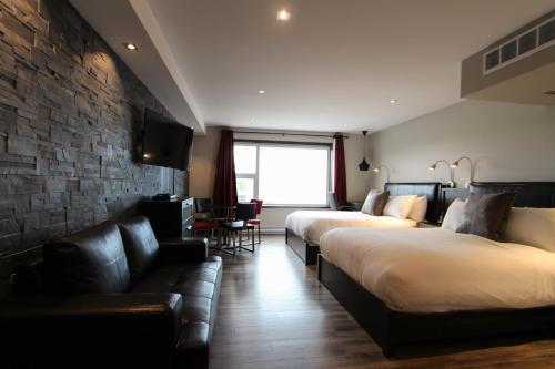 Habitación de hotel con 2 camas y sofá en Hôtel Saint-Germain Rimouski, en Rimouski