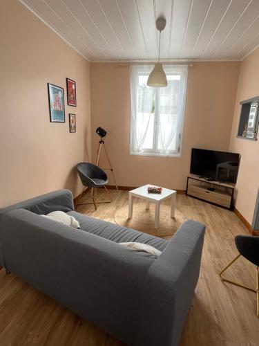 a living room with a couch and a tv at Charmante maison proche centre in Albert