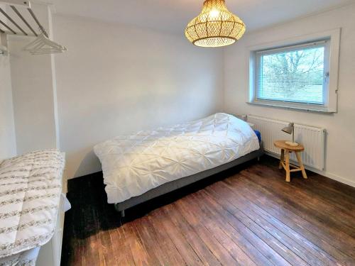 a bedroom with a bed and a window and a chandelier at de Brabander in Cadzand