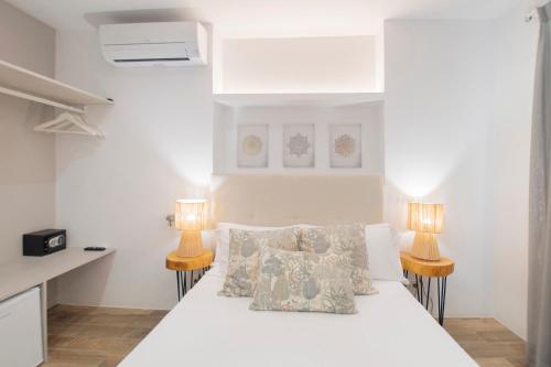 a bedroom with a white bed with two lamps at Hostal Perla Blanca Altea in Altea