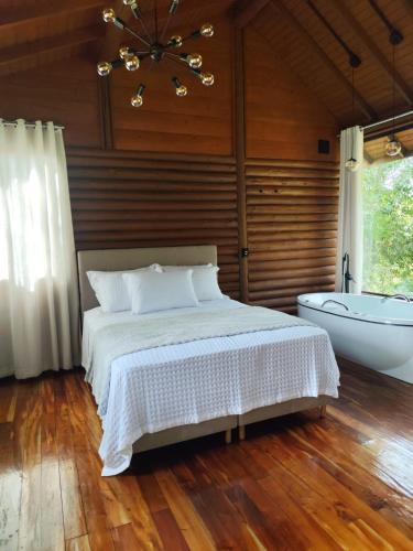a bedroom with a bed and a bath tub at Refugio Poço do Cânion in Barracão