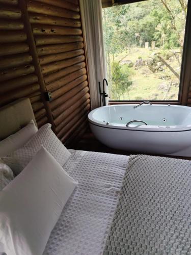 a bathroom with a tub and a bed and a window at Refugio Poço do Cânion in Barracão