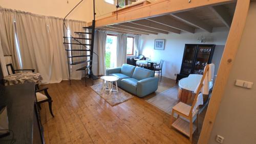a living room with a blue couch and a spiral staircase at Areal Botanika in Unhošť