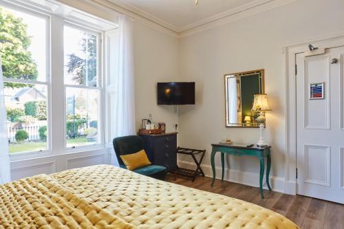 a bedroom with a bed and a chair and a window at Merlindale in Crieff