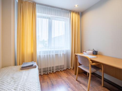 a bedroom with a desk and a bed and a window at RVR Smart Apartments Riga with Free Parking and Self Check-in in Rīga