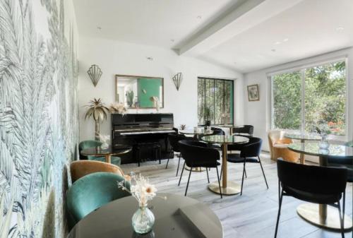 a living room with tables and chairs and a piano at Hôtel Paradis in Bormes-les-Mimosas
