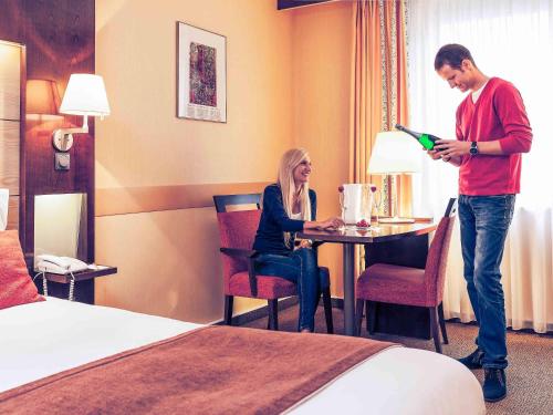 a man and woman sitting at a table in a hotel room at Mercure Budapest Korona in Budapest