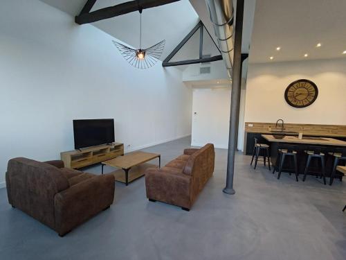 un salon avec un canapé, une télévision et une table dans l'établissement APPARTEMENT 4 CHAMBRES loft industriel, à Cholet