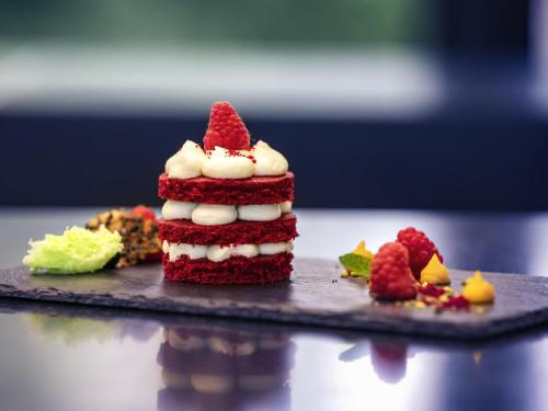 a red velvet cake with whipped cream and strawberries on a plate at Mercure Budapest Korona in Budapest