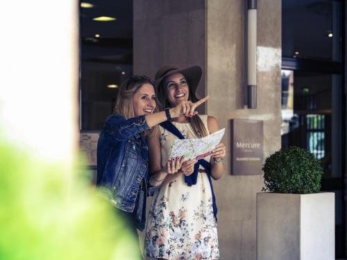 two women standing next to each other looking at a map at Mercure Budapest Korona in Budapest