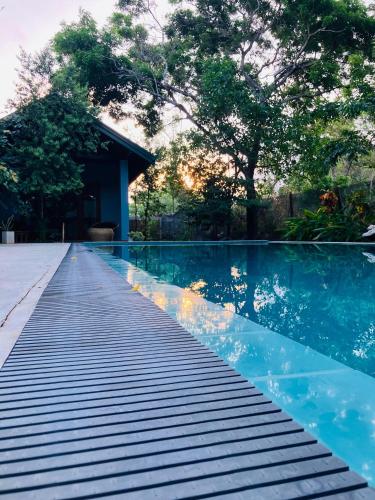 a swimming pool with a wooden walkway next to a house at Maritime Nest Cabanas in Tangalle