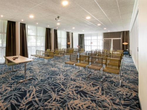 a conference room with chairs and a stage in it at Novotel Senart Golf De Greenparc in Saint-Pierre-du-Perray