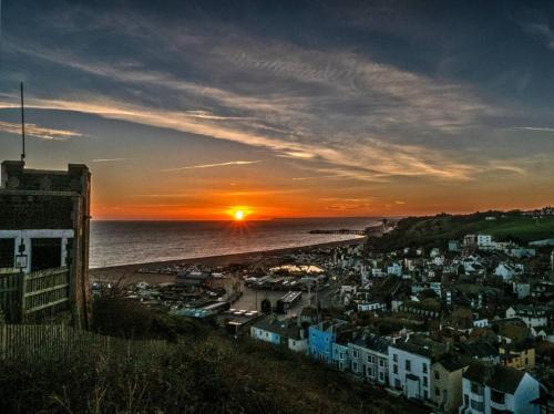 a sunset over a city with the ocean and houses at Coastal Victorian Apartment W Charm in Hastings