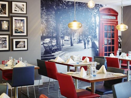 a restaurant with tables and a red phone booth at Novotel London Waterloo in London